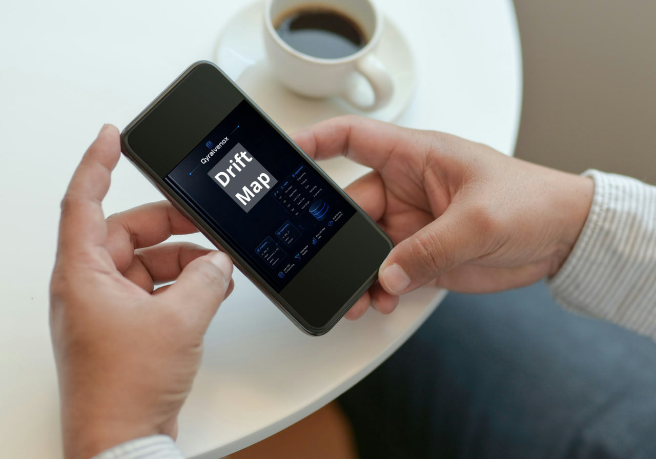 A person holds a smartphone displaying a drift map application over a white table, with a cup of coffee in the background.