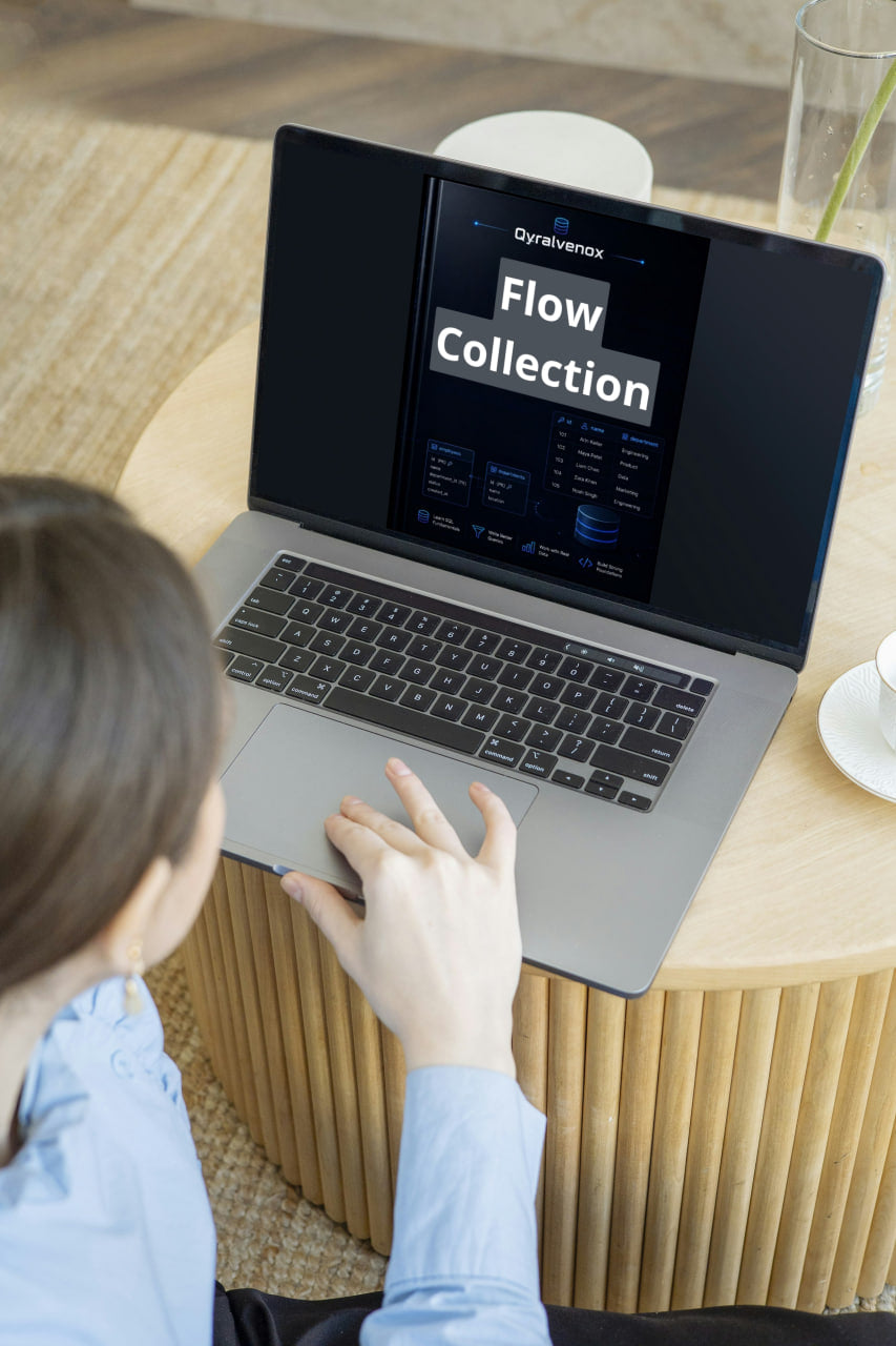 A person in a light blue shirt uses a silver laptop on a round wooden table in a modern indoor setting. The laptop screen displays a software interface titled 'Flow Collection' with the Dynavox logo.
